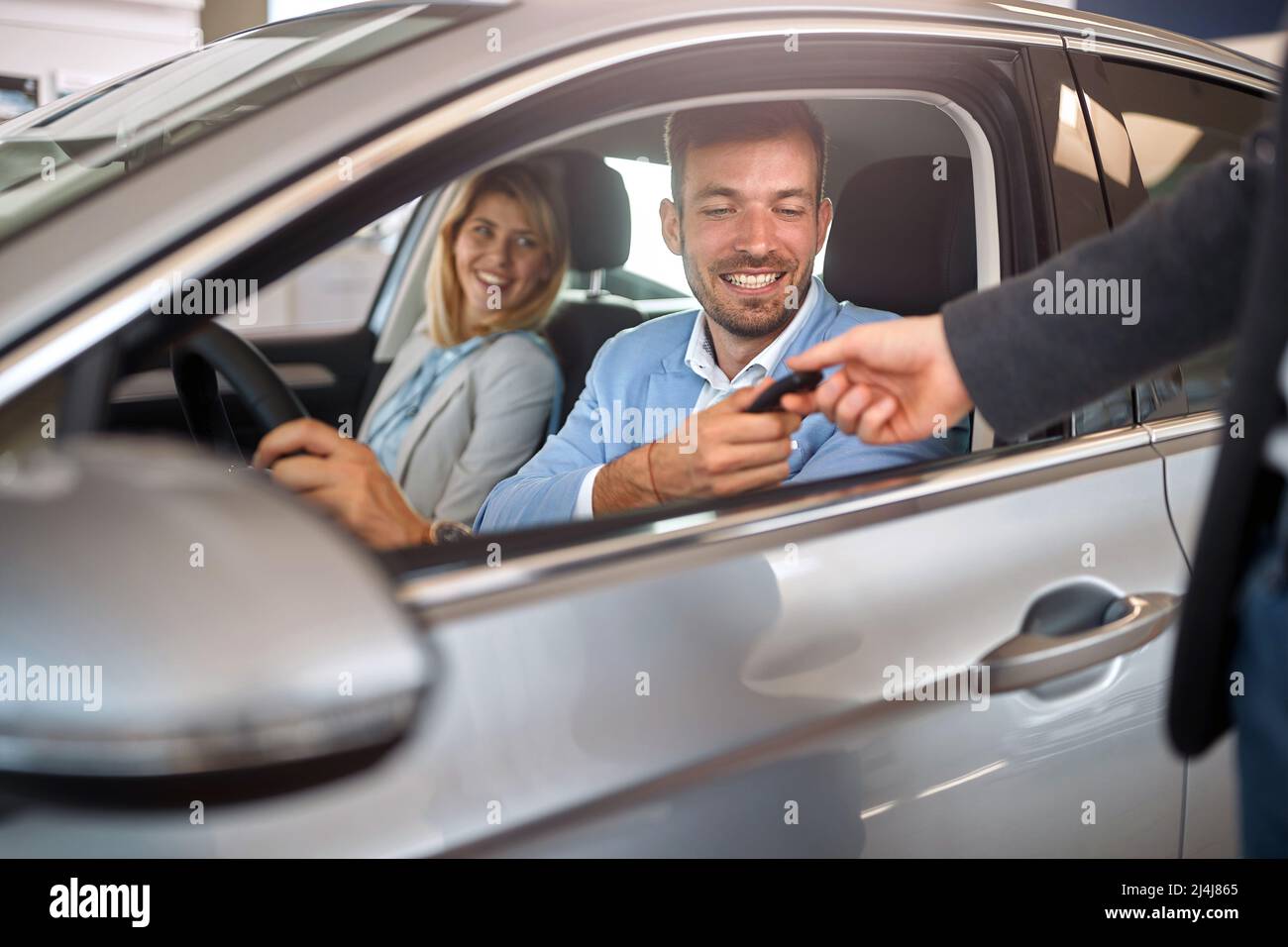 Acquirente con donna in auto nuova prendendo la chiave dal venditore Foto Stock