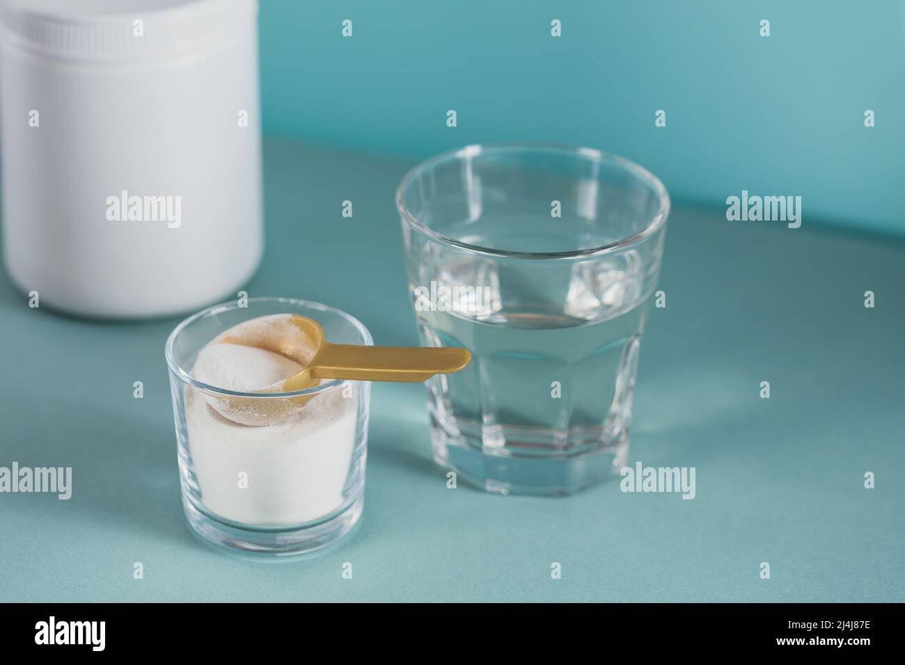 Vetro con collagene disciolto in acqua e collagene proteina in polvere su tabella di colore azzurro Foto Stock