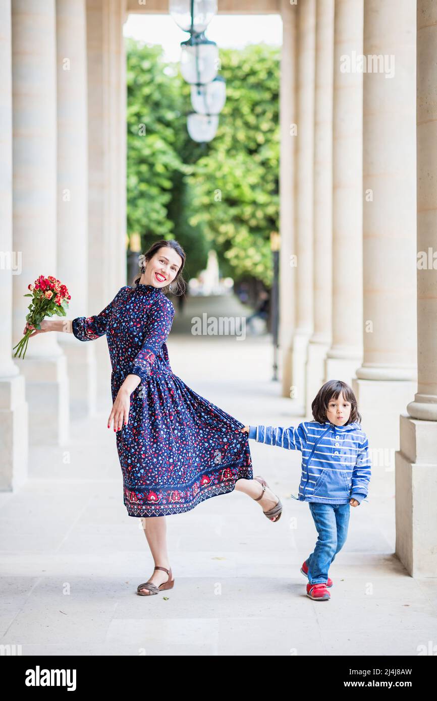 Ritratto di donna elegante in un abito blu in posa con il suo sole accanto ad un edificio cittadino con colonne Foto Stock