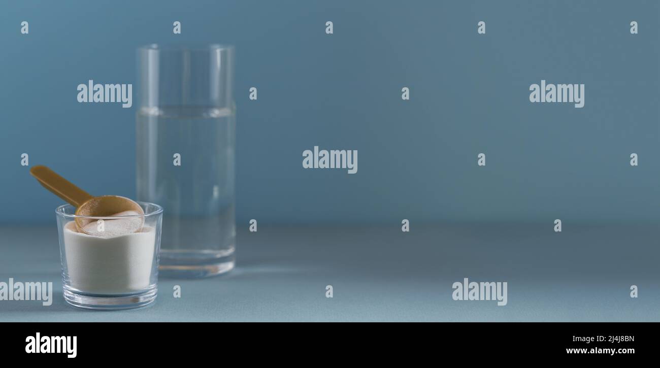 Polvere di collagene in ciotola, bicchiere d'acqua e misurino il cucchiaio su sfondo azzurro Foto Stock