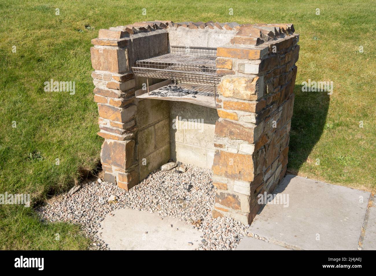 Un barbecue costruito in pietra, visto all'aperto in una giornata di sole, che illustra lo stile di vita della cucina all'aperto. Foto Stock