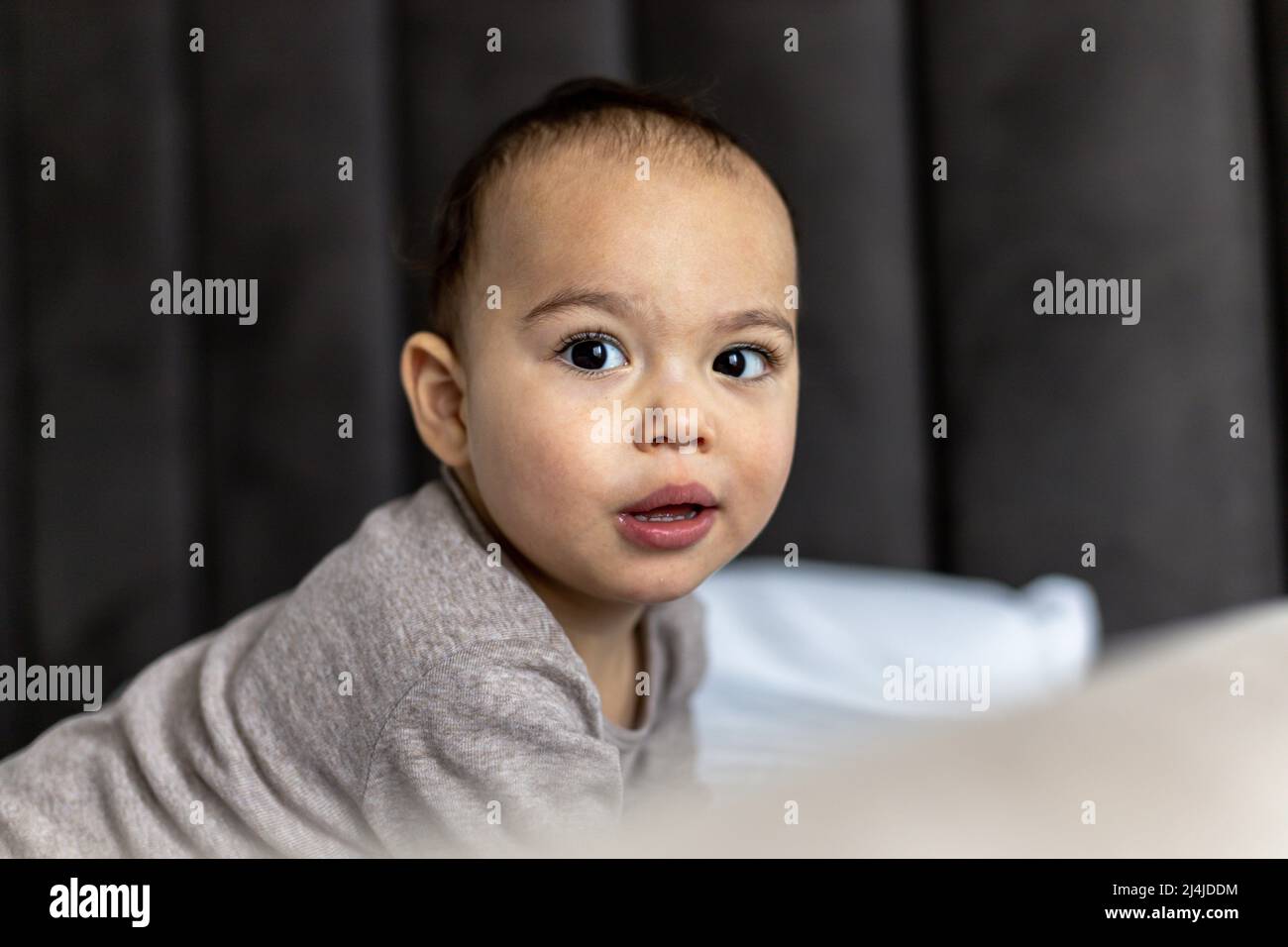 Bambino dolce sul letto. Faccia divertente di bambino chubby Foto Stock