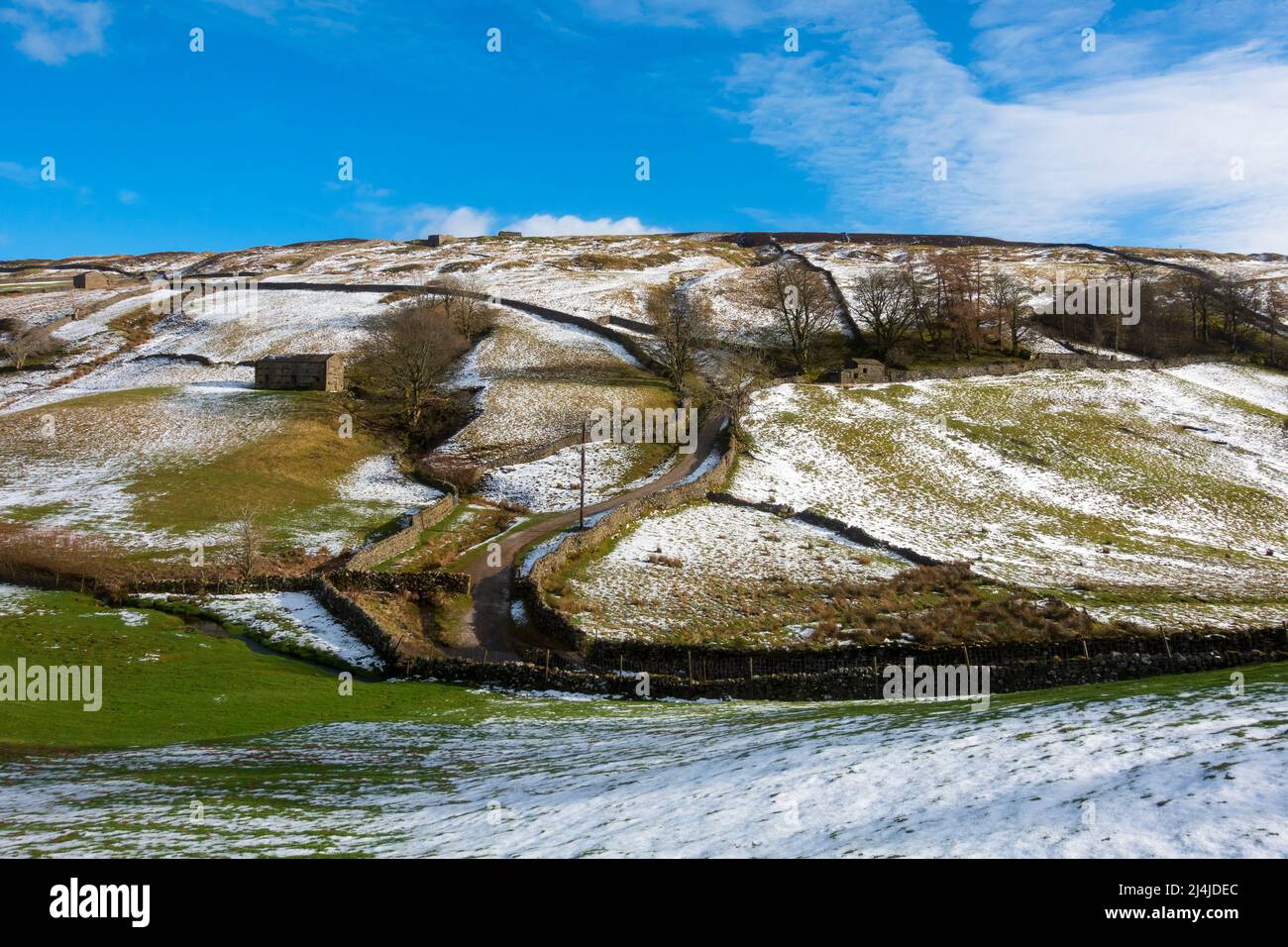 Fienili di pietra e colline innevate a Swaledale, Yorkshire Dales National Park. Foto Stock