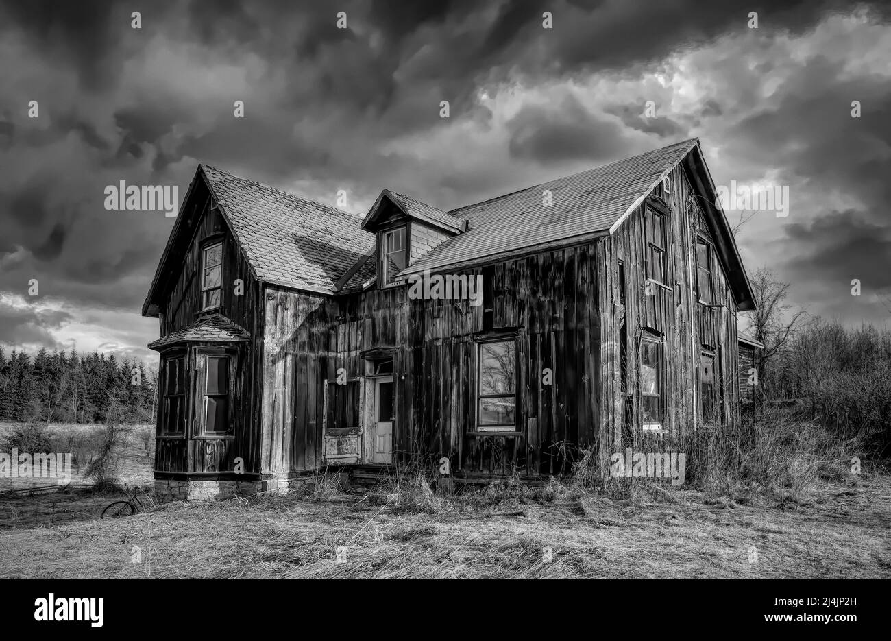 Un vecchio nero e bianco abbandonato spooky cercando fattoria in inverno su un cortile fattoria nel Canada rurale Foto Stock