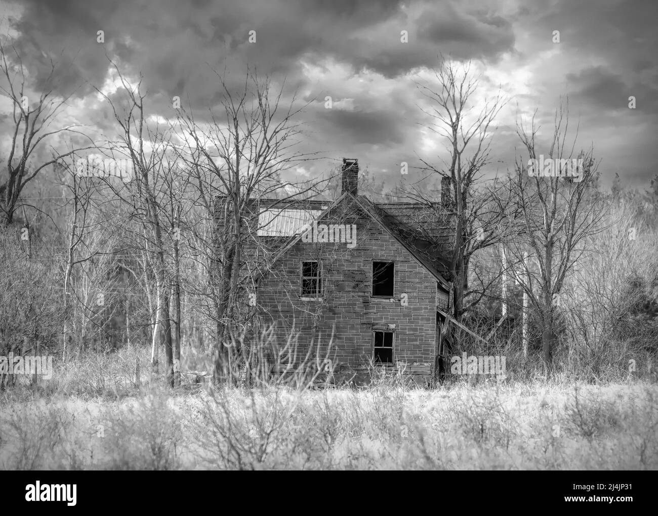 Un vecchio nero e bianco abbandonato infestato spoky aspetto fattoria in inverno su un cortile fattoria nel Canada rurale Foto Stock