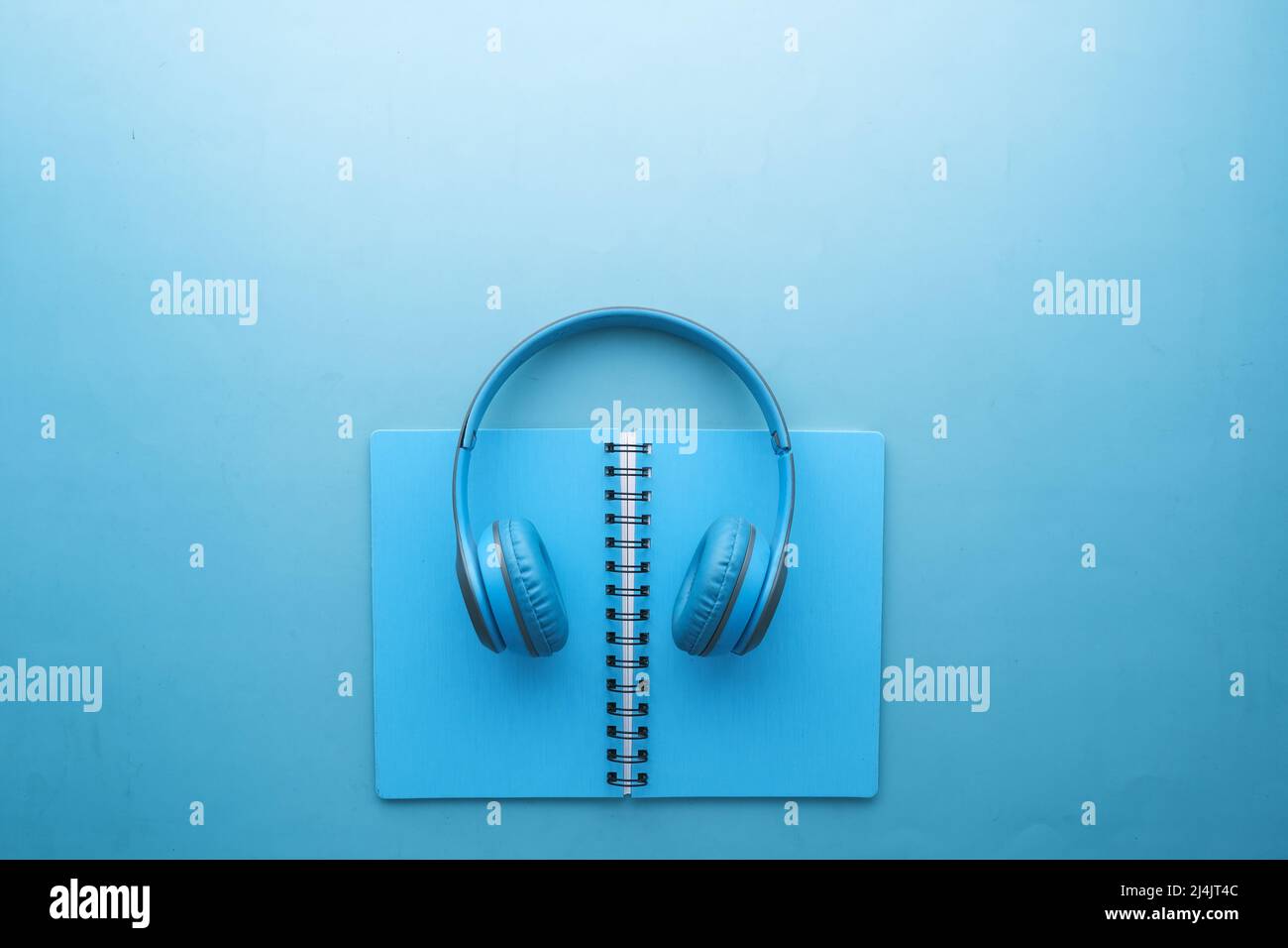 Concetto di audiolibro. Cuffie e blocco note su sfondo bianco Foto Stock