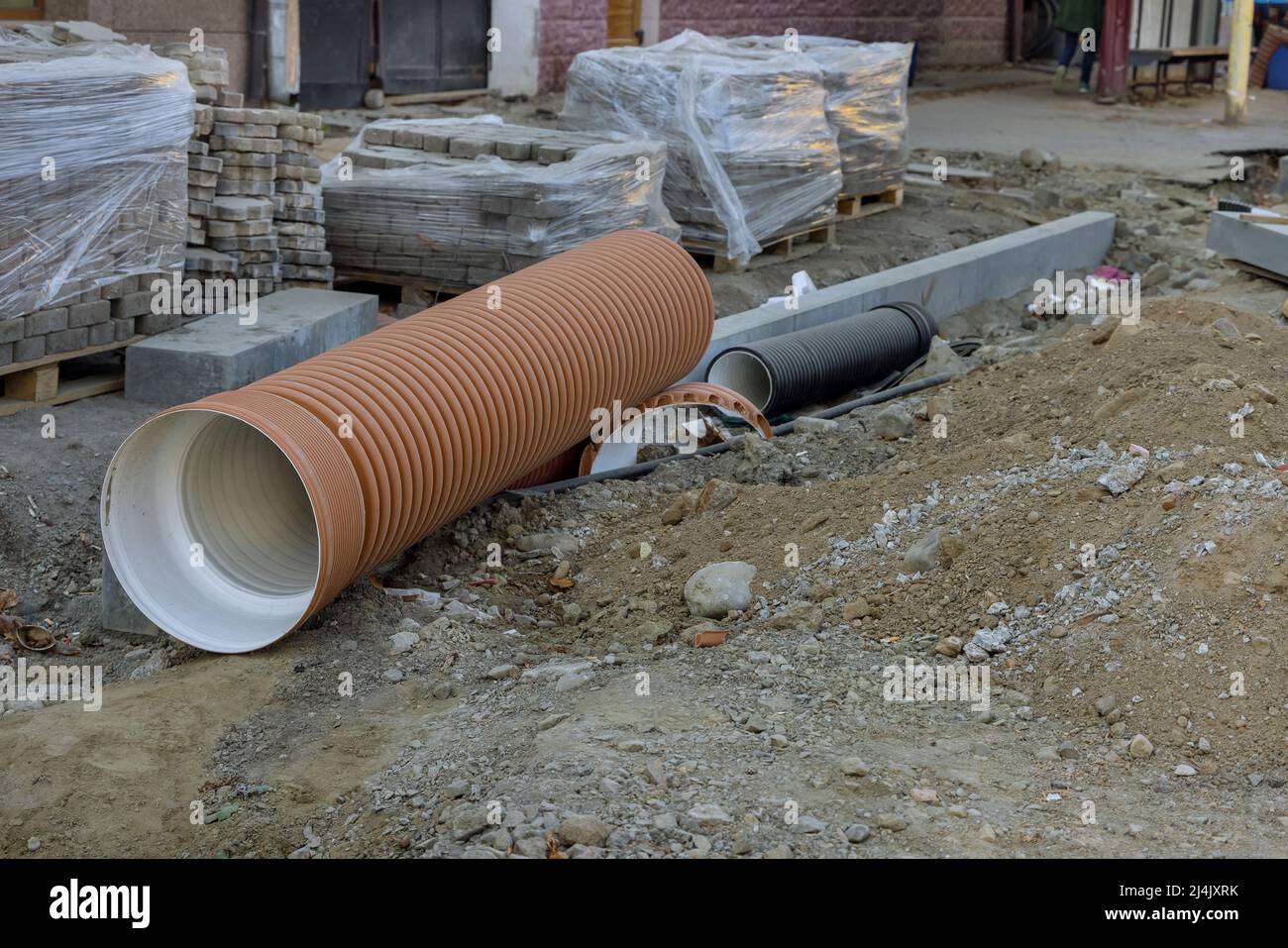 Tubo in attesa di installazione per la posa della ricostruzione stradale mediante riparazione di utenze Foto Stock