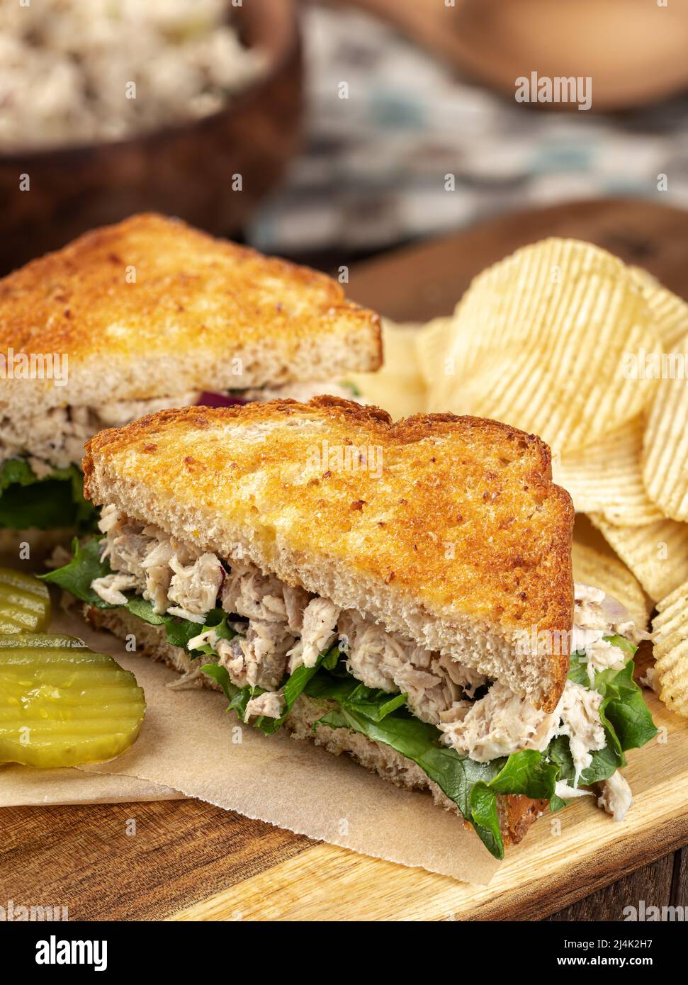 Sandwich con insalata di tonno con lattuga su pane tostato intero tagliato a metà su un tagliere Foto Stock