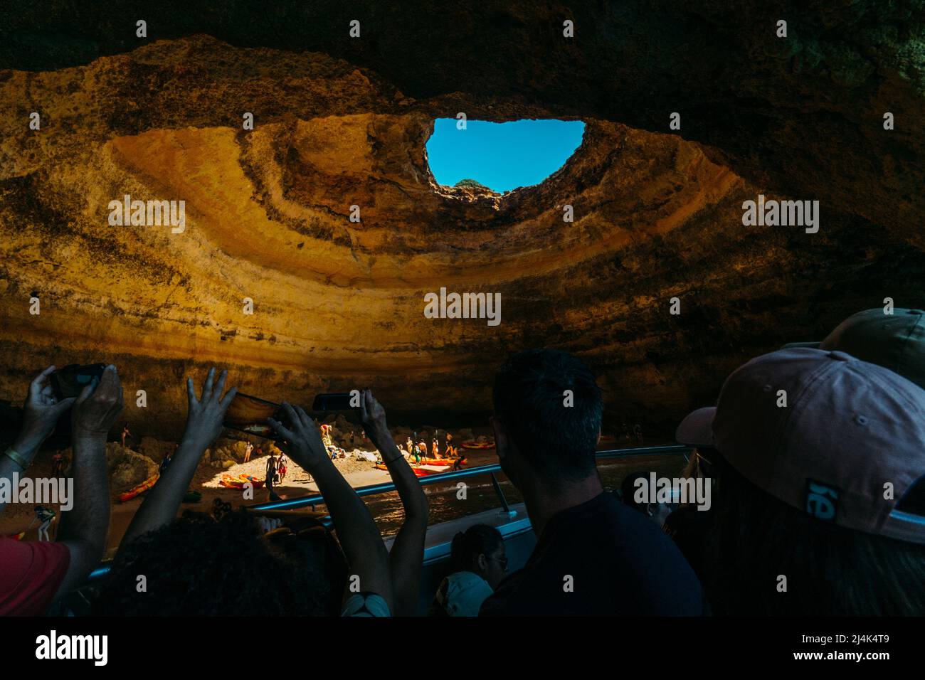 I turisti scattano foto della famosa grotta di Algar de Benagil, caratterizzata da un lucernario naturale e da un piccolo tratto di sabbia Foto Stock