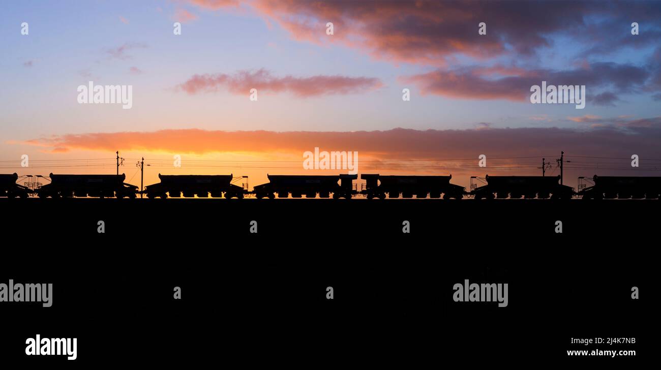 Silhouette di vagoni auto-blaster HQA Network Rail al tramonto sulla linea principale della costa occidentale Foto Stock