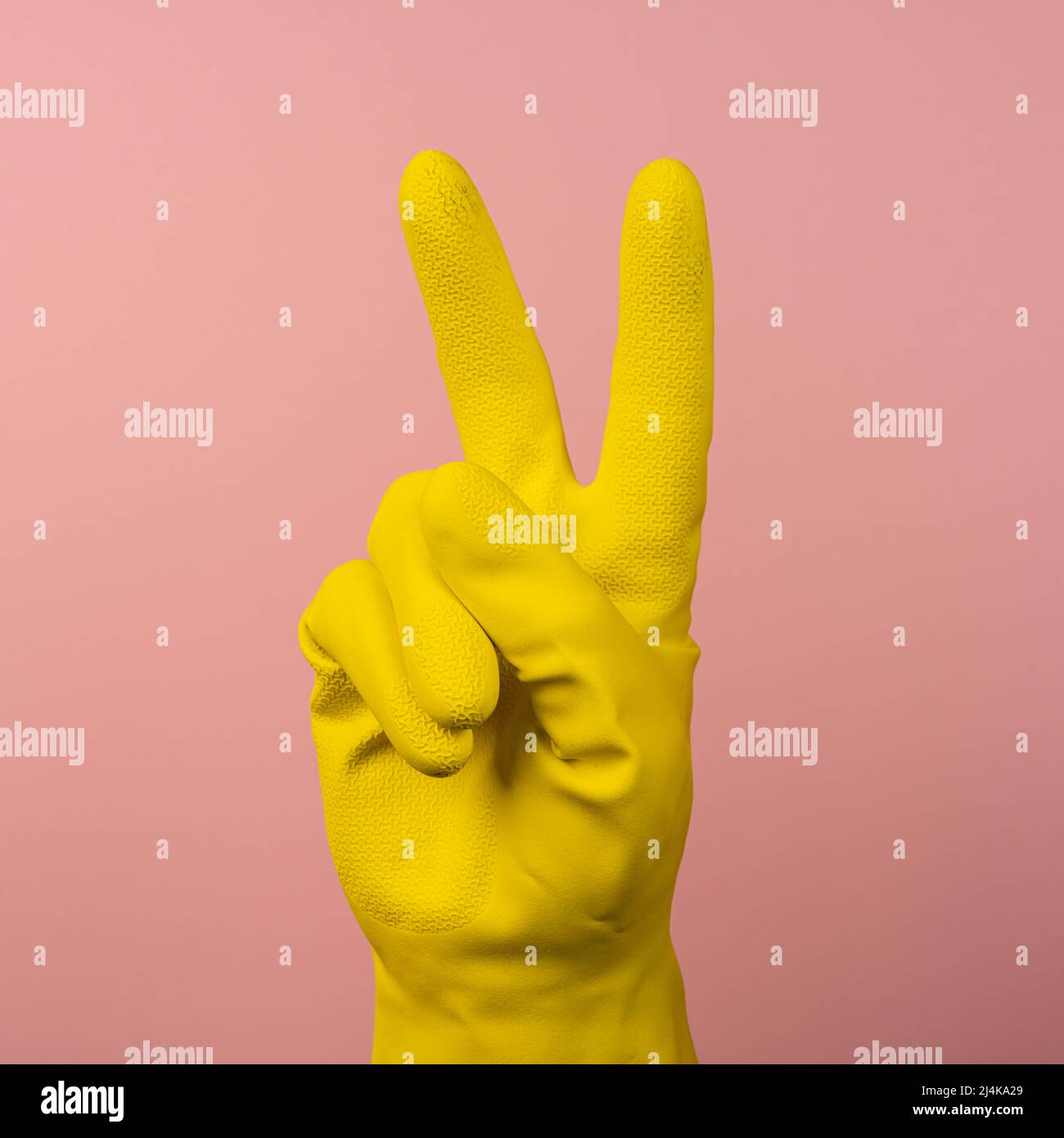 Il gesto V fatto con una mano che indossa un guanto di gomma giallo Foto Stock