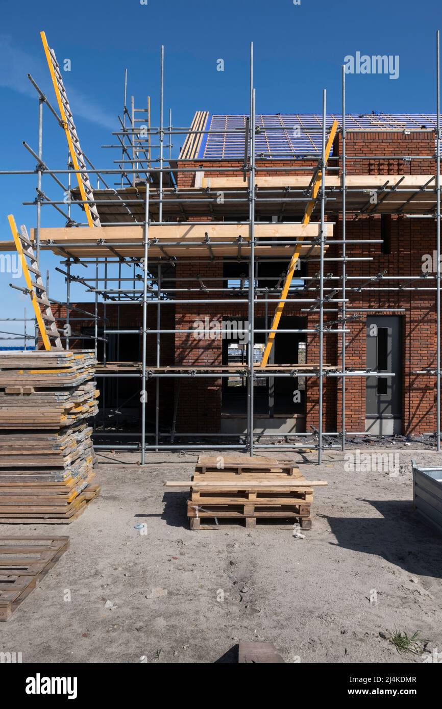 Piattaforma di impalcatura contro una fila di case di recente costruzione in un cantiere. Ci sono scale per salire da una piattaforma all'altra Foto Stock