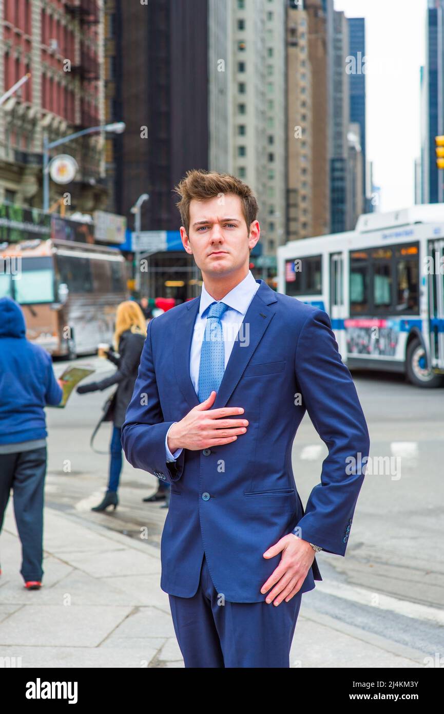 Vestito in un abito blu sottile, cravatta a motivi geometrici e sotto la camicia  blu chiaro, un giovane uomo d'affari si trova su una strada in una grande  città Foto stock -