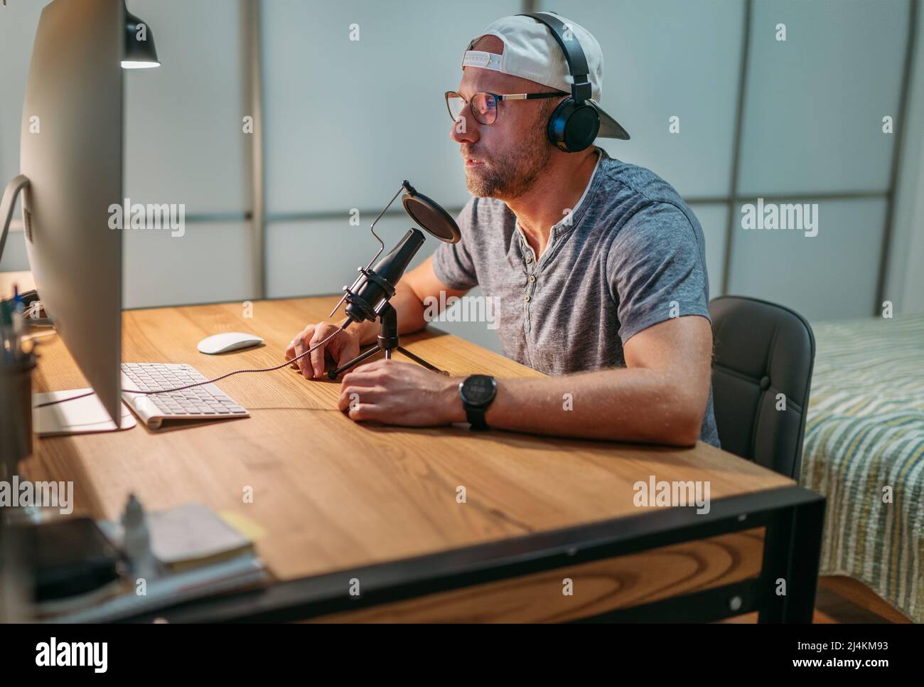 Uomo medio-vecchio Blogger in cuffie leggere testo registrazione voce o fare online webinar o annuncio di notizie. Recor audio moderno da studio Foto Stock