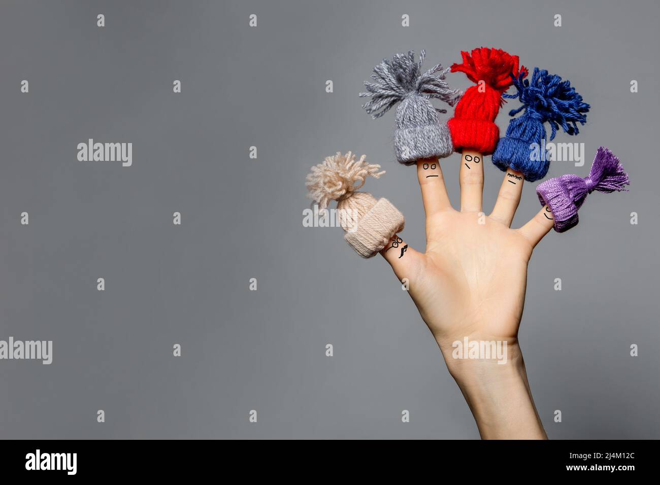 Divertente famiglia di dita in cappelli in maglia su grigio Foto Stock