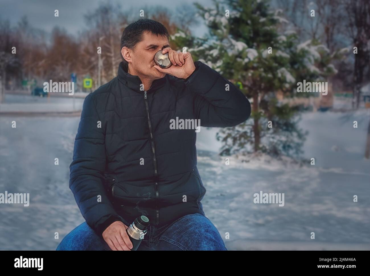 un uomo in un inverno freddo beve caffè da un thermos e riposa Foto Stock