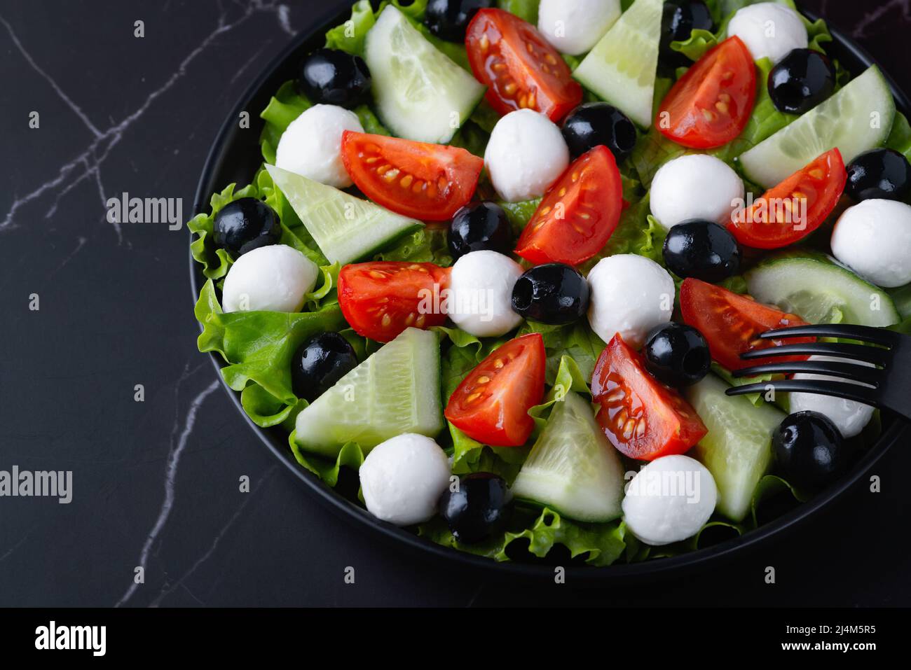 Insalata fresca con cetrioli, pomodori, olive nere e formaggio feta o mozzarella Foto Stock