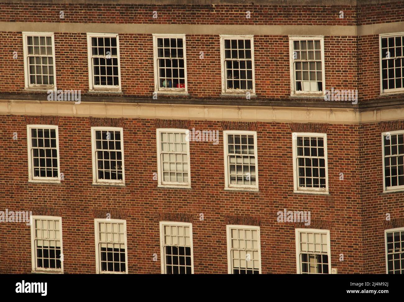 Una vista da una finestra all'ottavo piano che guarda ad un vecchio edificio in mattoni per uffici con vecchie finestre in legno di Kingston upon Thames, Londra Foto Stock