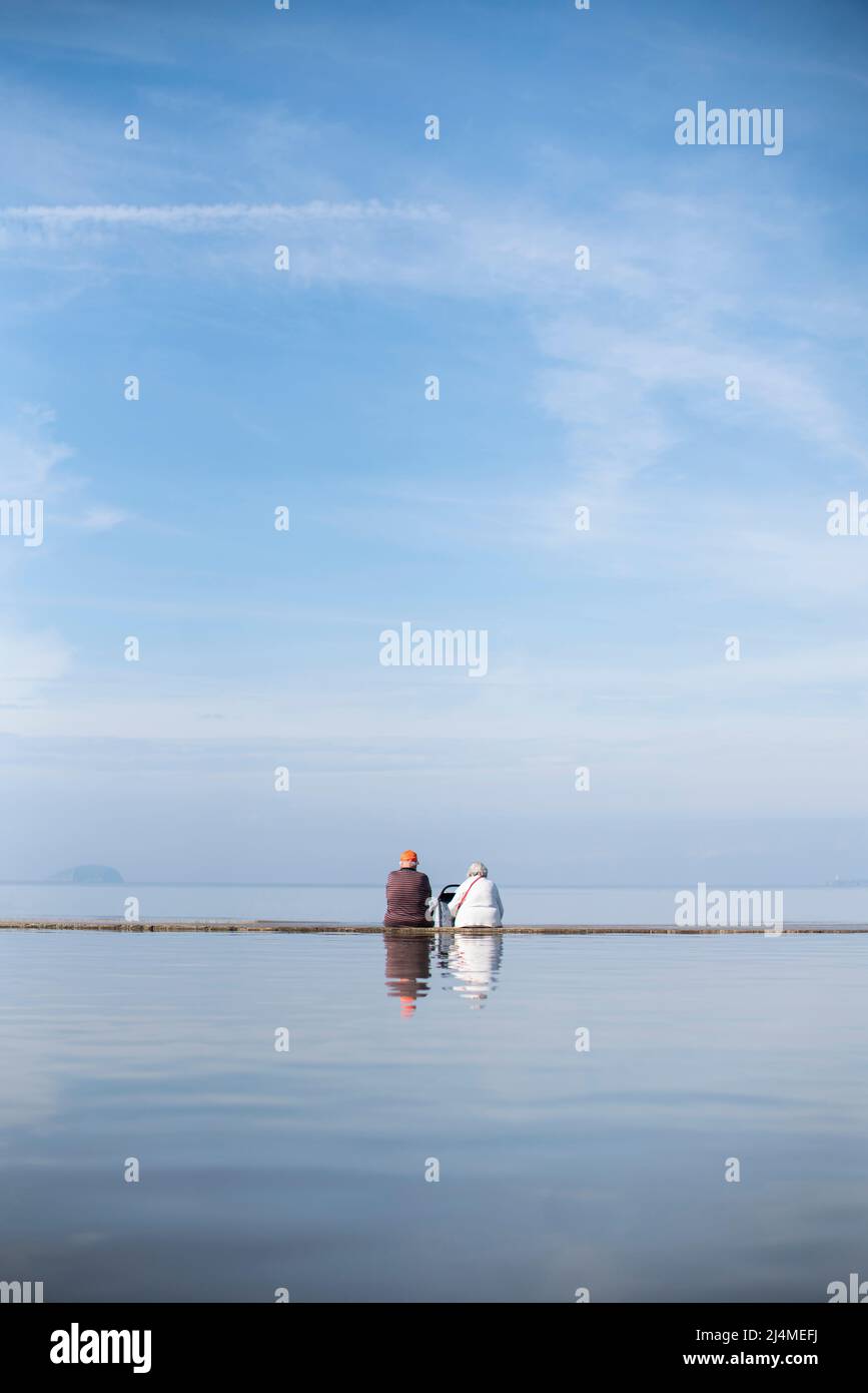 Una coppia anziana si siede sulla spiaggia a Weston-super-Mare, Somerset Foto Stock