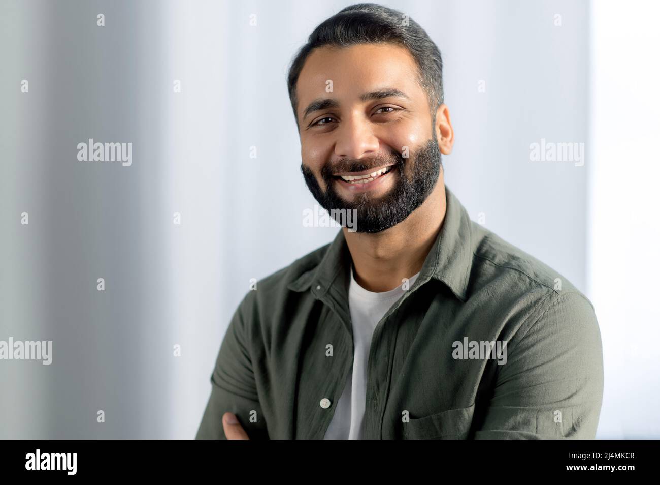 Ritratto di indiano o arabo positivo businessman di successo, manager, freelancer, lavoratore d'ufficio, indossare casual elegante camicia, stand in un ufficio moderno, sorridente amichevole alla macchina fotografica Foto Stock