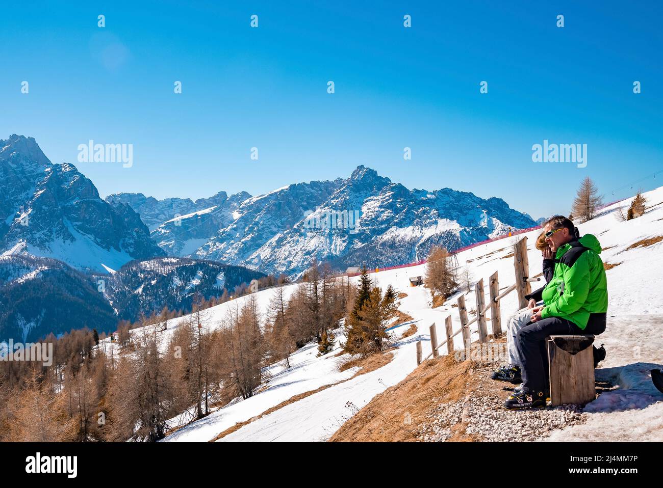 Coppia rilassante su panchina in alta montagna in giornata di sole durante le vacanze sciistiche Foto Stock