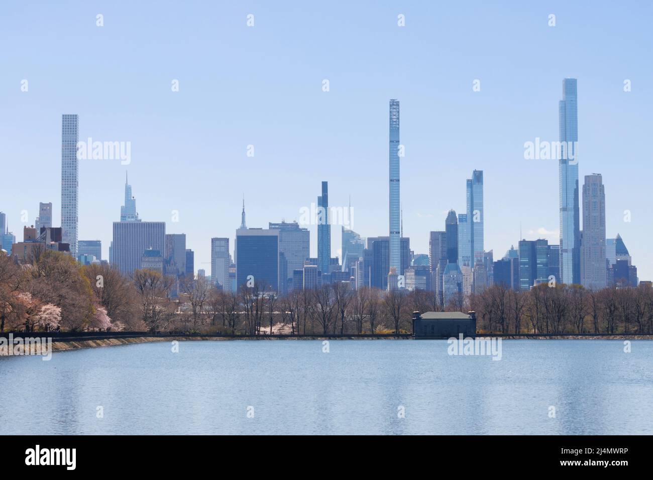 Panorama dello skyline della fila di miliardari visto attraverso il bacino idrico di Central Park con un cielo blu chiaro Foto Stock