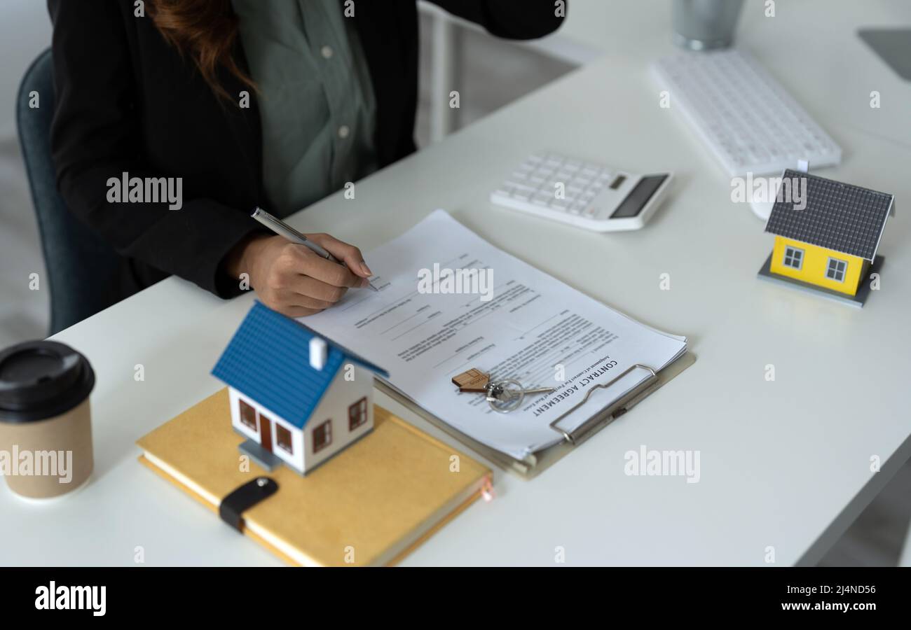 Business donna asiatica firma il contratto dietro il modello architettonico casa - concetto immobiliare Foto Stock