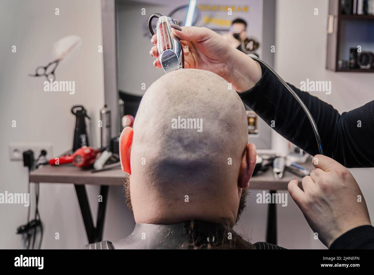 L'uomo caucasico di mezza età sta tagliando i propri capelli con un rasoio elettrico. Foto Stock