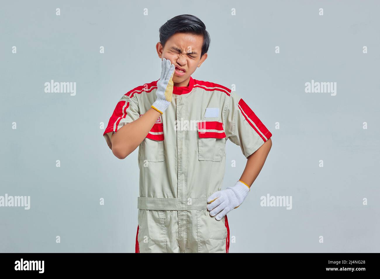 Ritratto di bell'uomo con bocca meccanica uniforme a contatto con espressione dolorosa su sfondo grigio Foto Stock