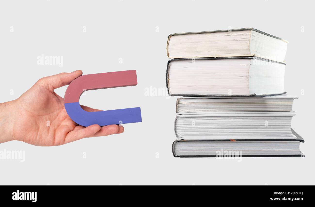 Donna mano che tiene magnete vicino a libri stack. Attrarre, ottenere conoscenza, saggezza dalla lettura. Concetto di istruzione e studio. Foto di alta qualità Foto Stock