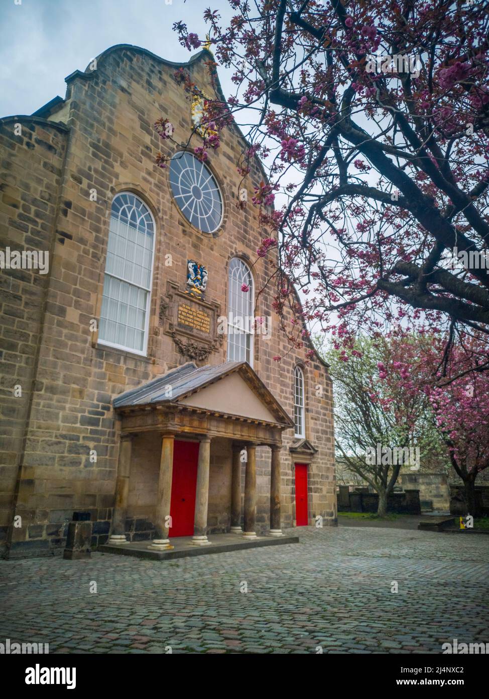Canongate Kirk, Canongate, Royal Mile, Edimburgo, Regno Unito. 16th Apr 2022. REGNO UNITO. Meteo. Una fioritura di ciliegi rosa alle porte d'ingresso di Canongate Kiek sul Royal Mile di Edimburgo. La Kirk of the Canongate, o Canongate Kirk, serve la Parrocchia di Canongate nel centro storico di Edimburgo, in Scozia. È una congregazione della Chiesa di Scozia. La parrocchia comprende il Palazzo di Holyroodhouse e il Parlamento scozzese. Credit: phil wilkinson/Alamy Live News Foto Stock