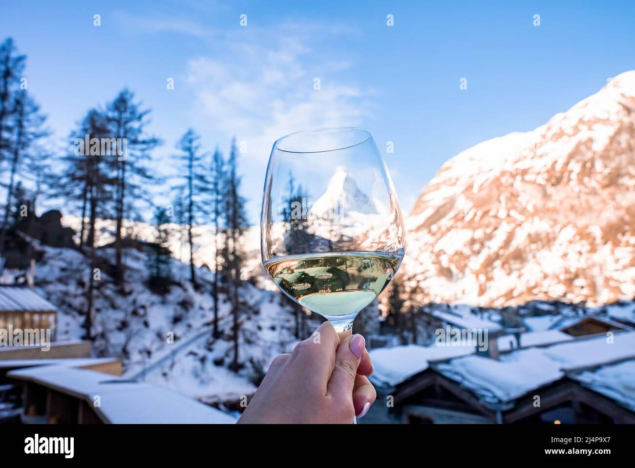 Donna che tiene il wineglass contro il paesaggio di città coperto di neve e il Matterhorn bello Foto Stock