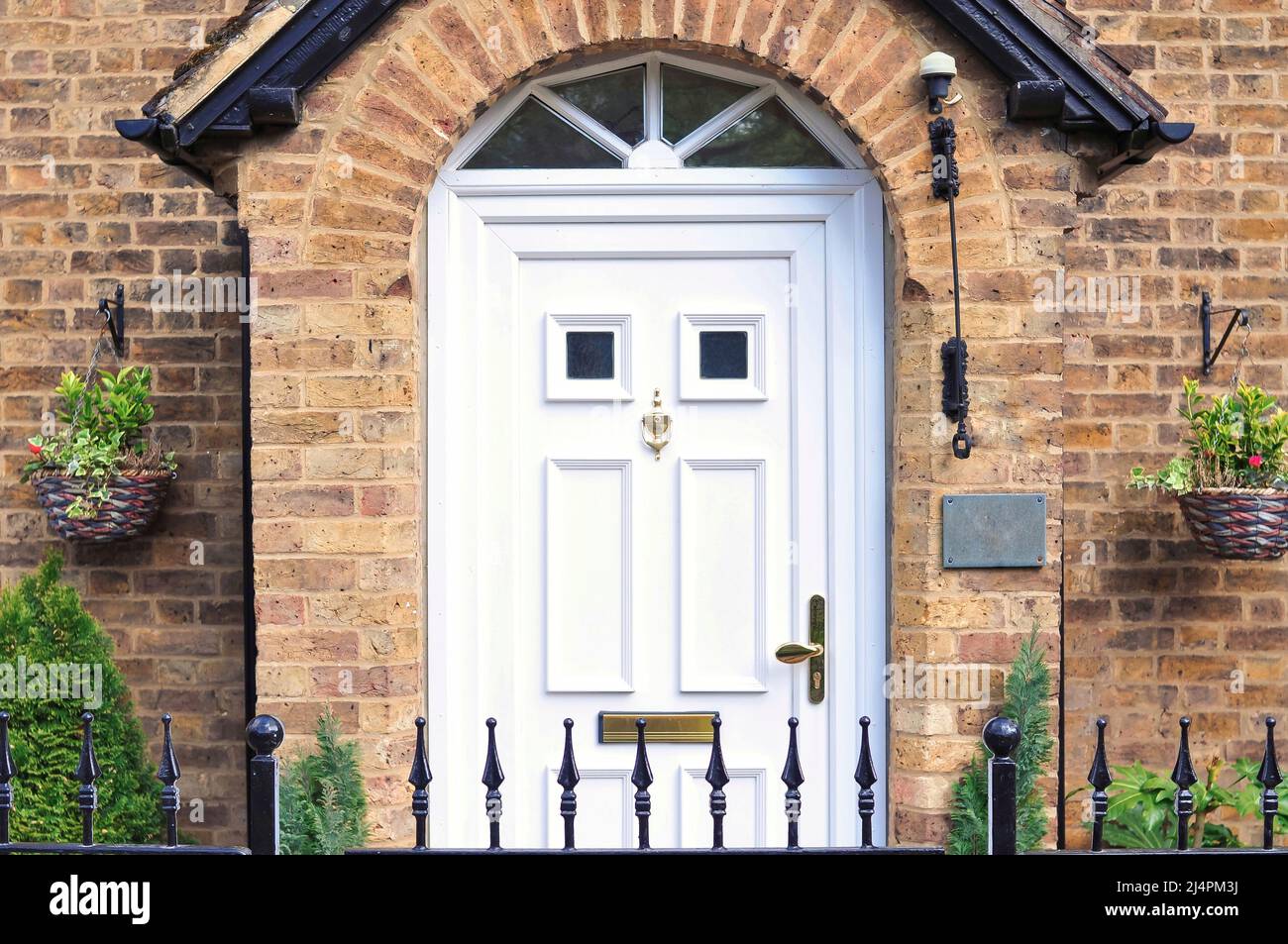 Ingresso di mattoni vecchia casa inglese con porta bianca e oro bussare Foto Stock