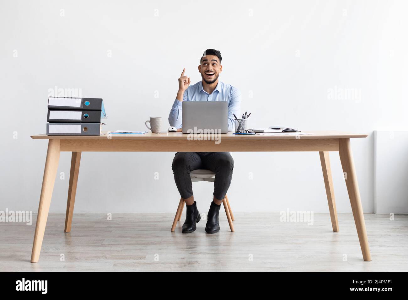 Idea di concetto. L'uomo eccitato che punta il dito verso l'alto sul posto di lavoro Foto Stock