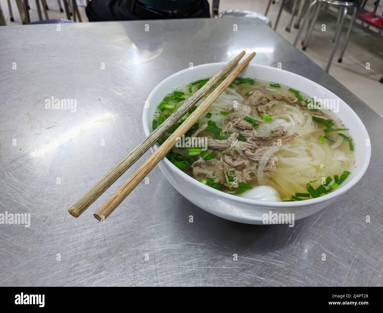 Pho Bo, una zuppa di noodle di manzo e riso servita in un ristorante con bacchette, Vietnam. Foto Stock