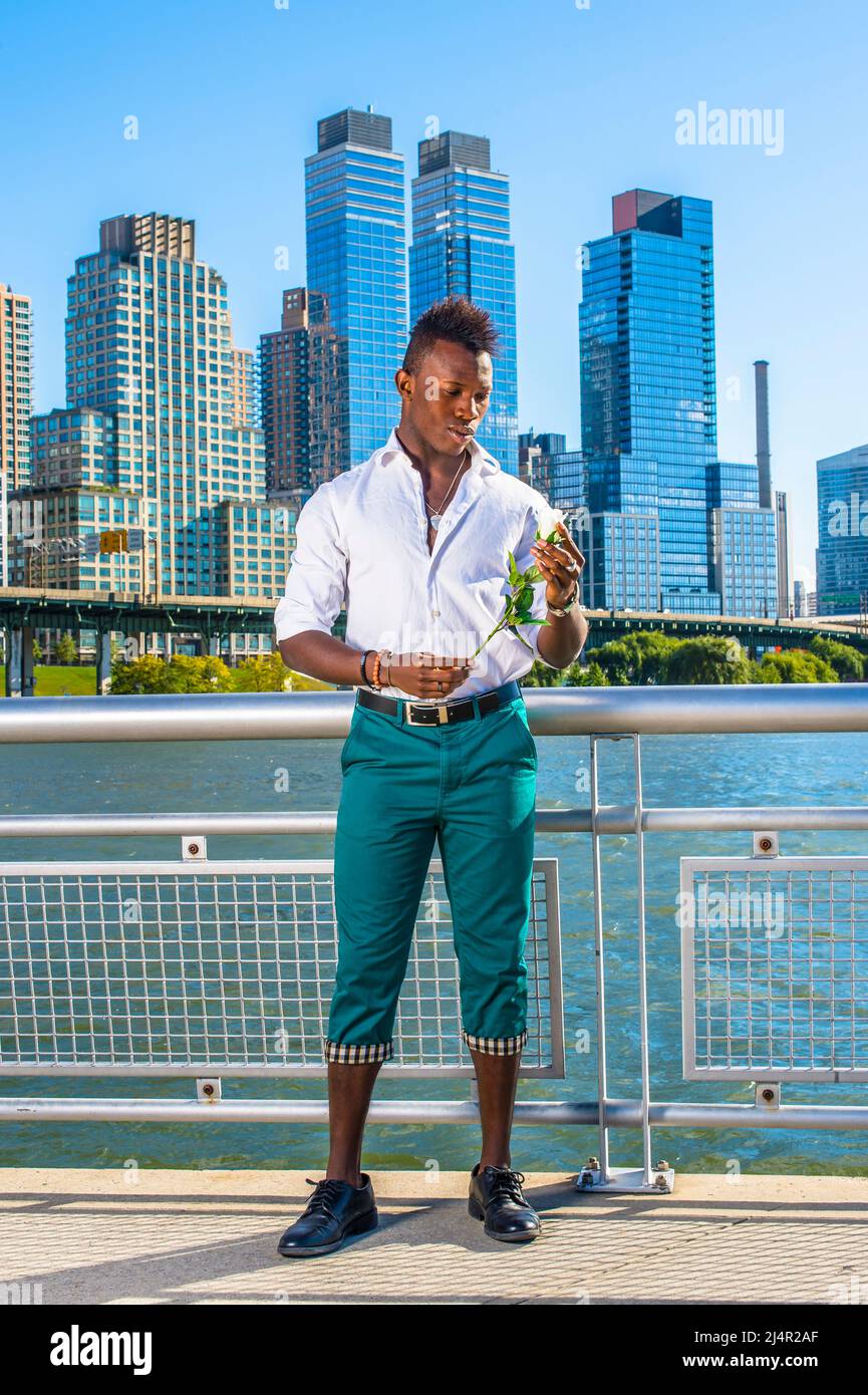 Amore per la città. Indossando una camicia bianca, pantaloni verdi, scarpe  in pelle, un giovane ragazzo nero con capelli mohawk è in piedi davanti  agli edifici, guardando un Foto stock - Alamy