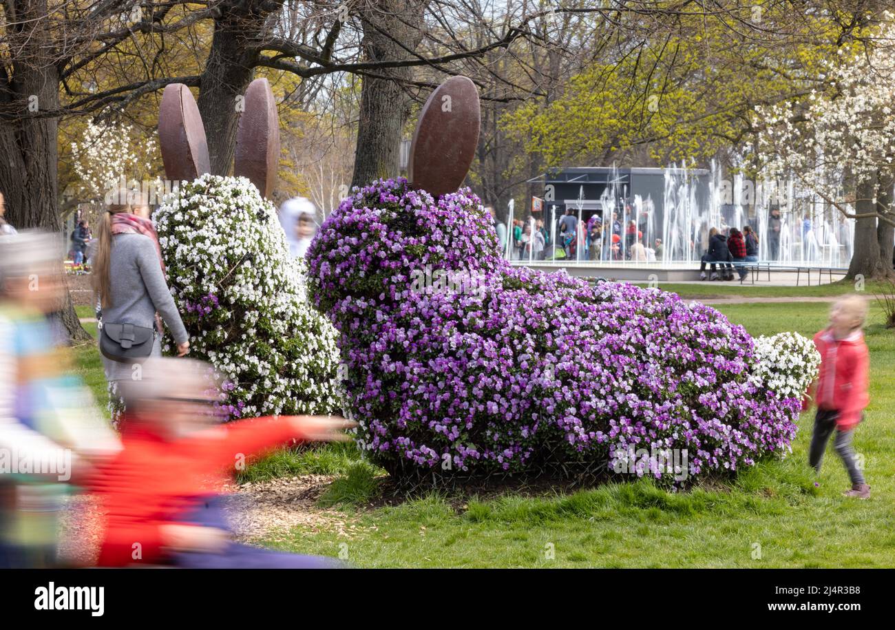 Erfurt, Germania. 17th Apr 2022. Le figure del coniglietto pasquale fiorito sono circondate da persone nel Parco Ega. La domenica di Pasqua tutti i bambini fino a 16 anni sono ammessi gratuitamente nel parco. Credit: Michael Reichel/dpa/Alamy Live News Foto Stock