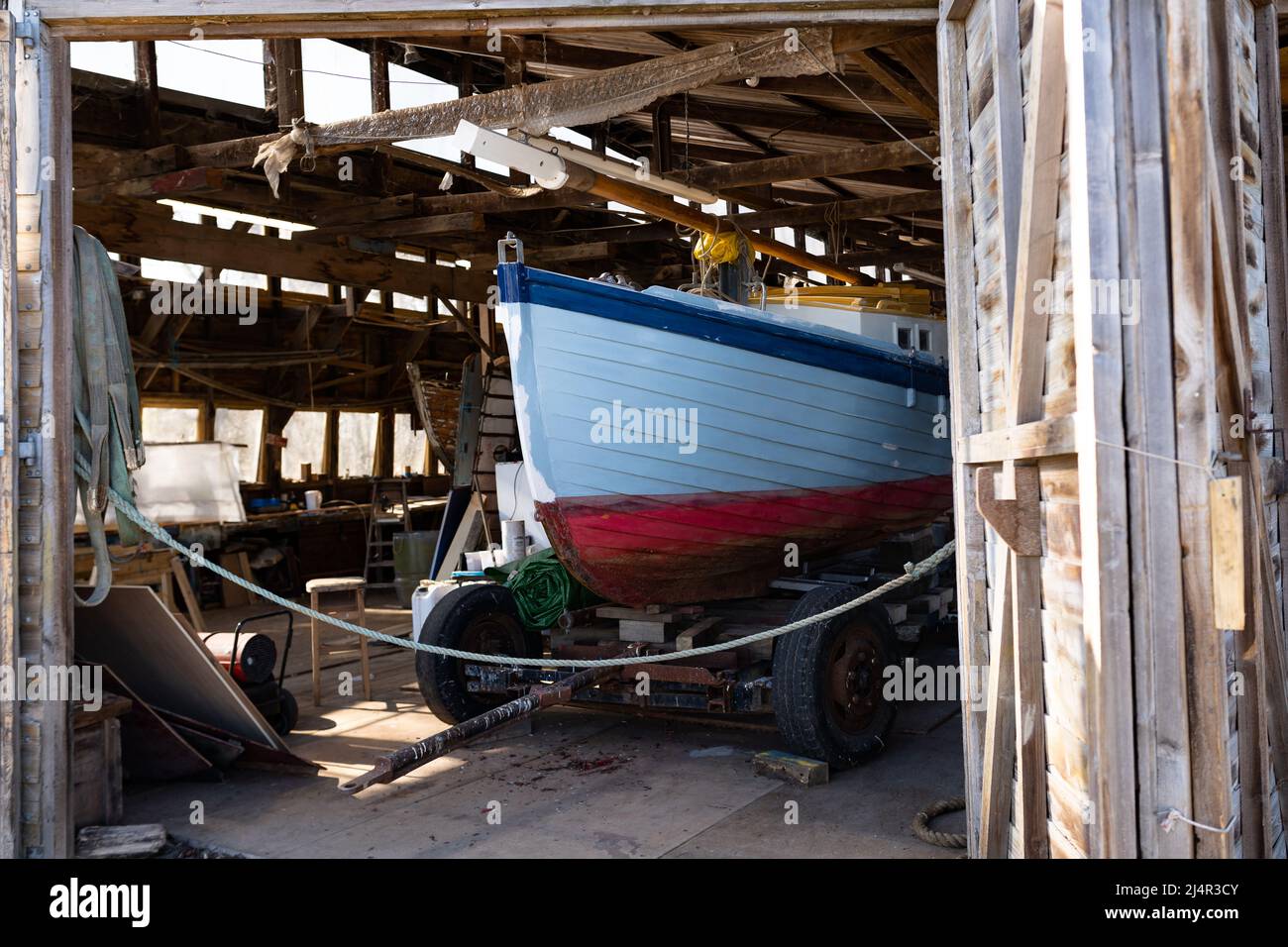 Tradizionale barca a vela in legno in un laboratorio in fase di lavoro e restauro Foto Stock