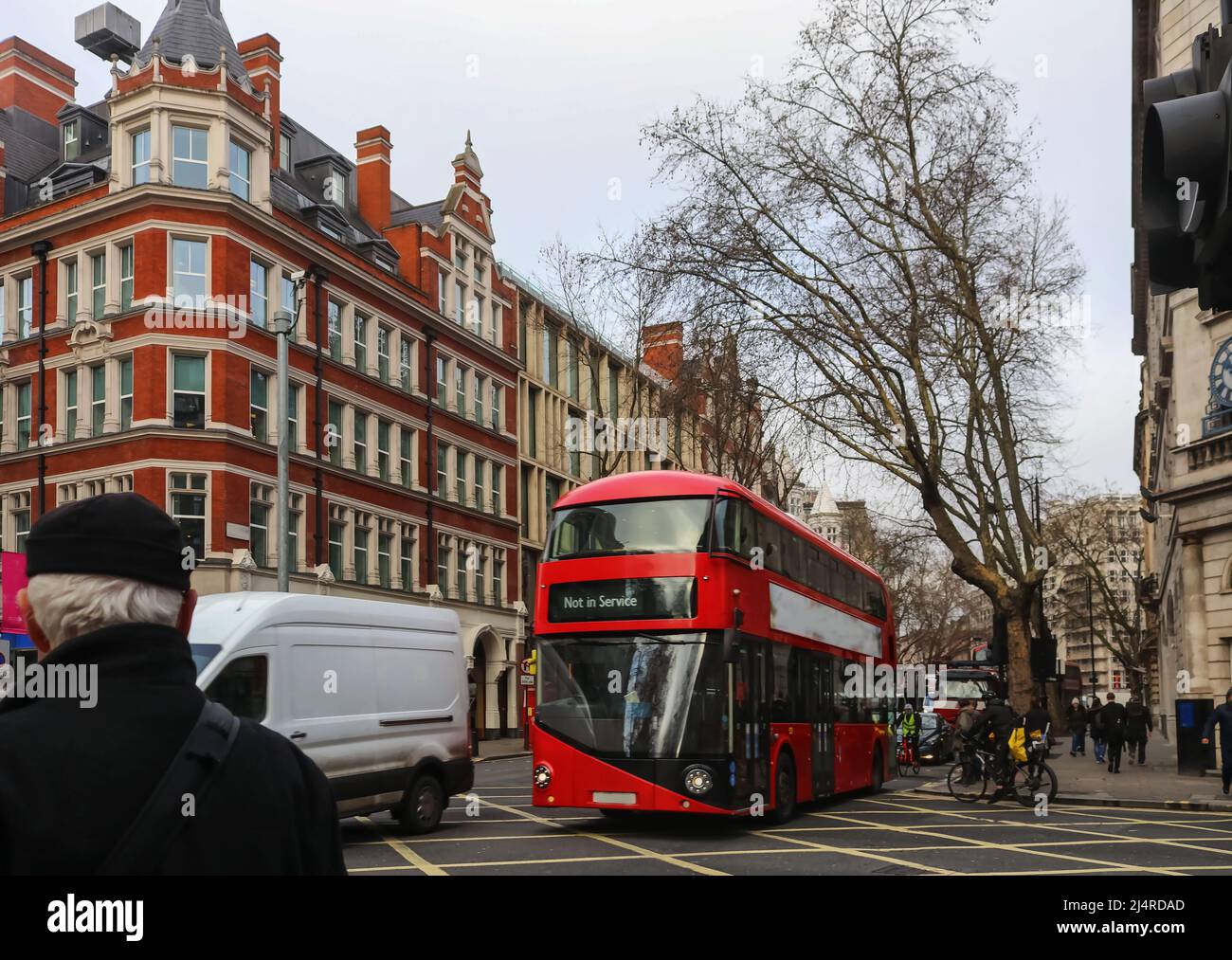 Incrocio trafficato di Londra in giornata invernale bagnata con persone in bici e autobus a due piani sulla strada - fuoco selettivo Foto Stock