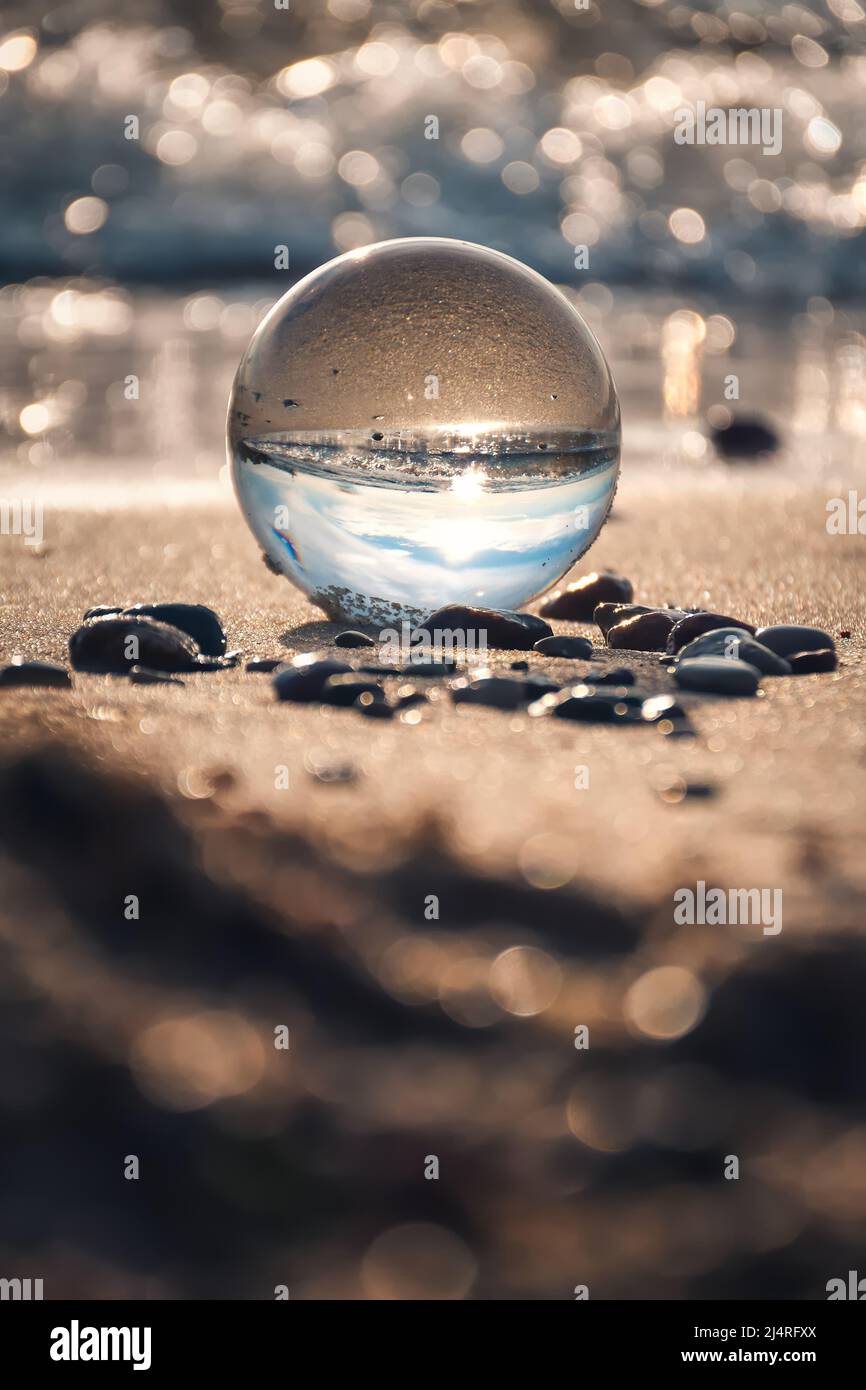Idea astratta di mare di vacanza. Paesaggio marino tenuto in una palla di vetro con uno sfondo sfocato. Foto Stock