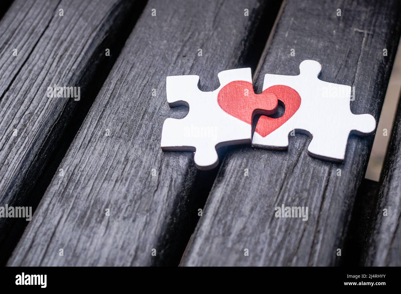 Il cuore rosso è disegnato sui pezzi del puzzle di legno che giacciono l'uno  accanto all'altro su sfondo di legno. Concetto di amore Foto stock - Alamy