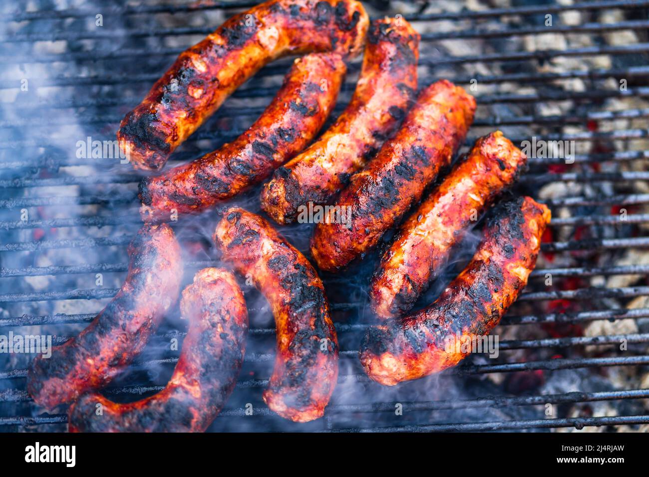 Grigliare le salsicce sulla griglia per barbecue. Deliziose salsicce sulla griglia al carbone Foto Stock