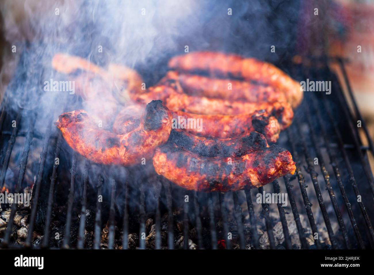 Grigliare le salsicce sulla griglia per barbecue. Deliziose salsicce sulla griglia al carbone Foto Stock
