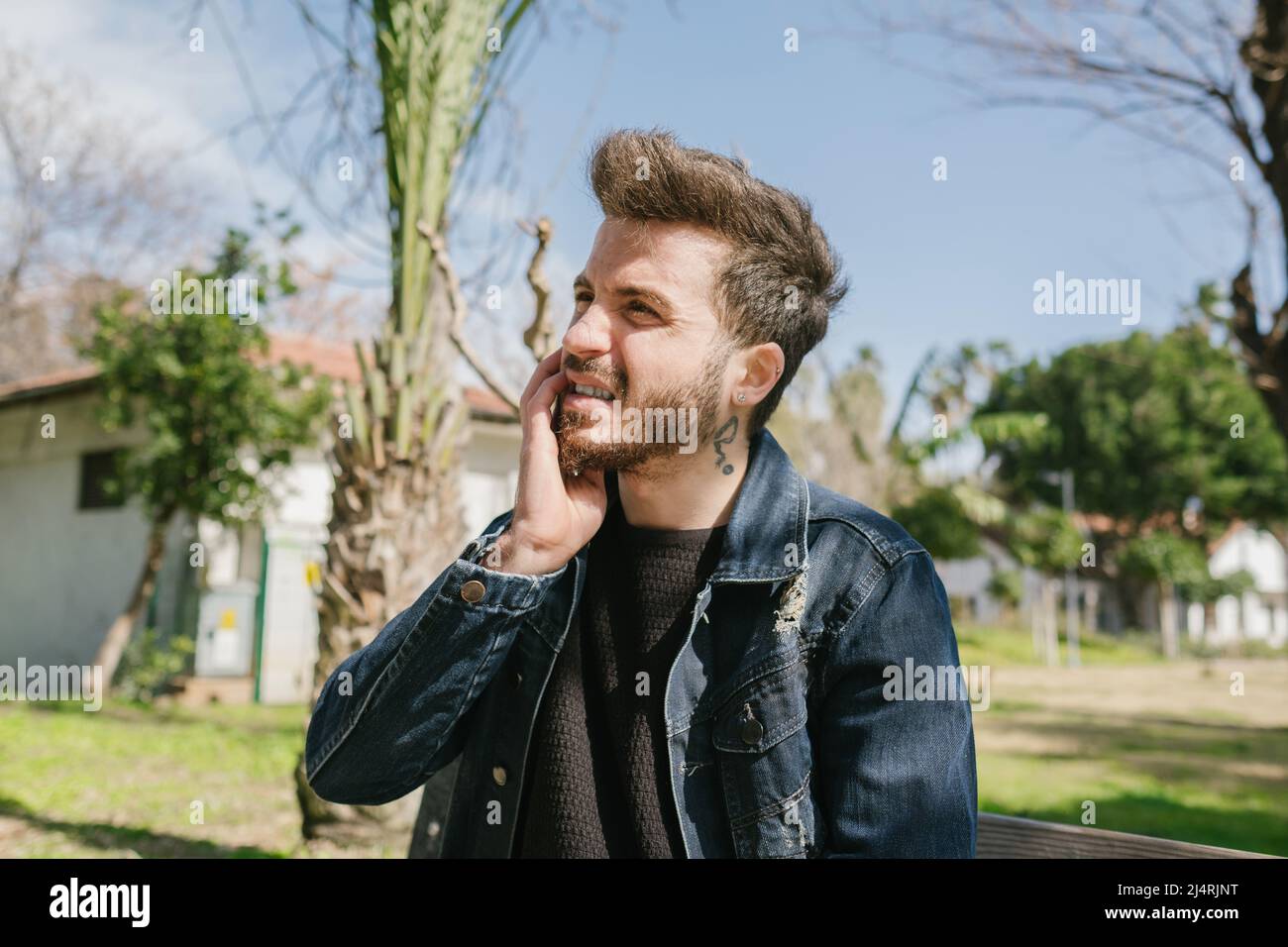 Mal di denti, giovane uomo che tiene il mento di fronte al dente dolorante, un giovane adulto con paura del dentista Foto Stock