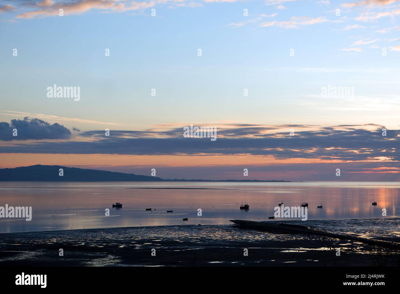 L'estuario del Dee qui visto al tramonto forma un confine tra la penisola di Wirral nell'Inghilterra nord-occidentale e il Flintshire nel Galles nord-orientale. Foto Stock