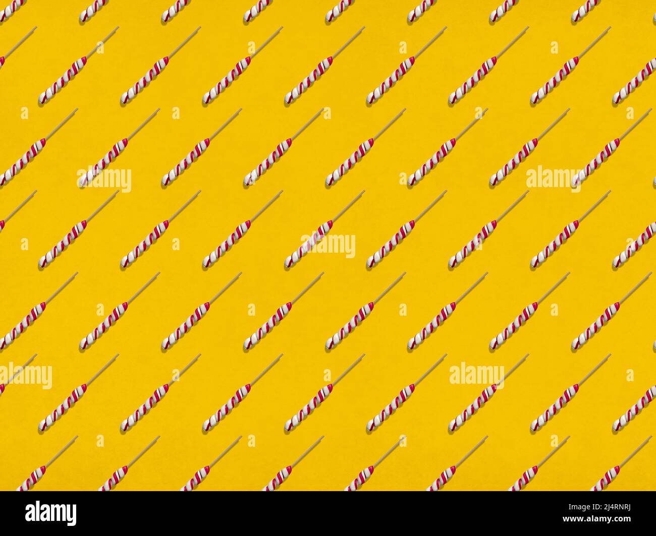 Molti lecca-lecca dolci disposti in file su sfondo giallo Foto Stock