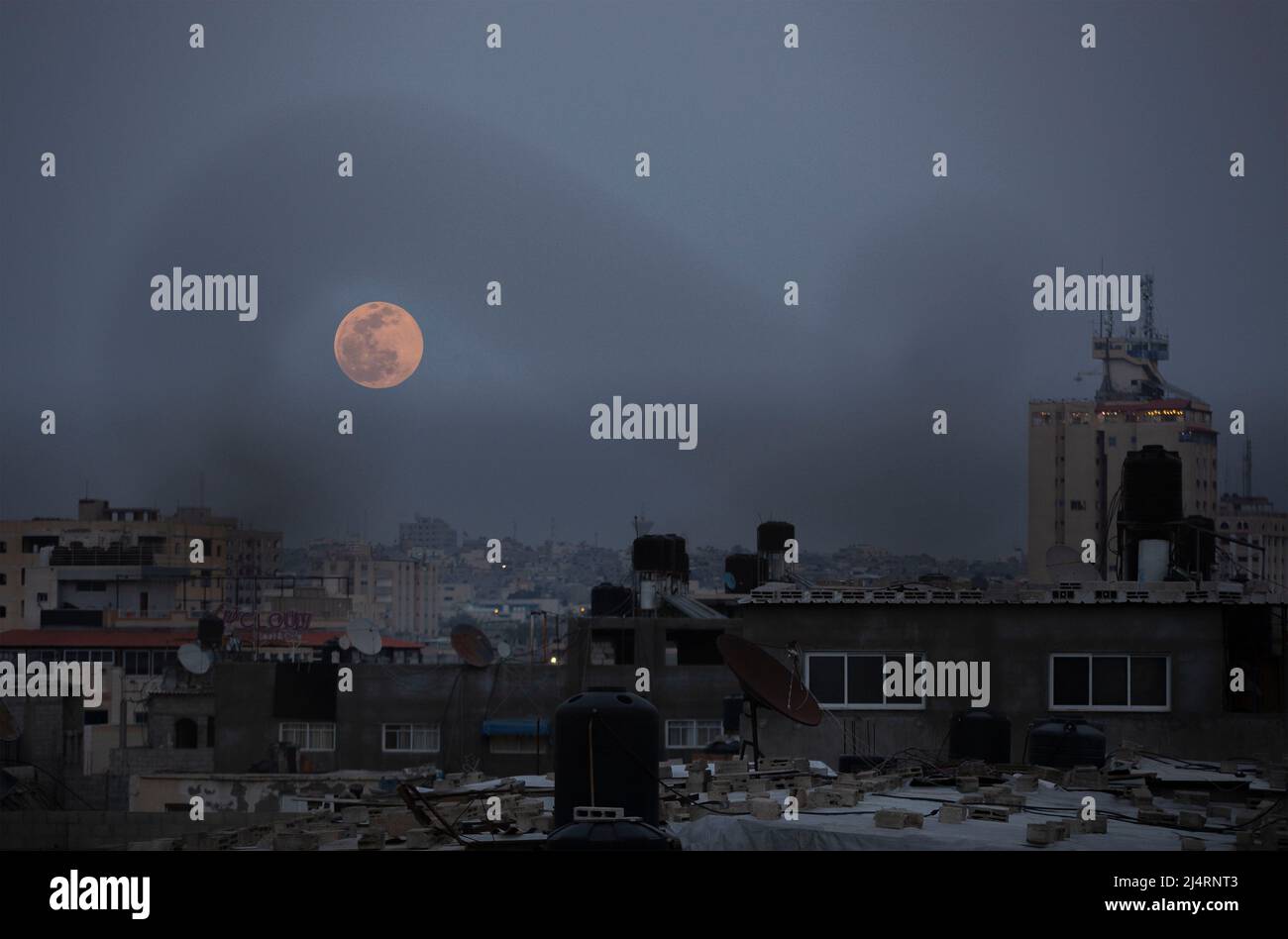 La piena "luna rosa" sorge sulla città di Gaza nel mezzo del Ramadan. Questo fenomeno astronomico può essere visto nella luna piena durante il mese di aprile dal tramonto fino all'alba. Gaza. Foto Stock