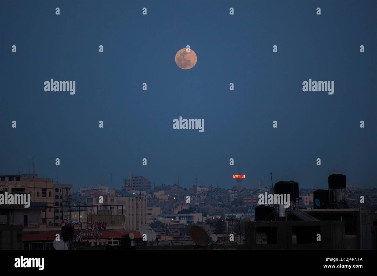 La piena "luna rosa" sorge sulla città di Gaza nel mezzo del Ramadan. Questo fenomeno astronomico può essere visto nella luna piena durante il mese di aprile dal tramonto fino all'alba. Gaza. Foto Stock
