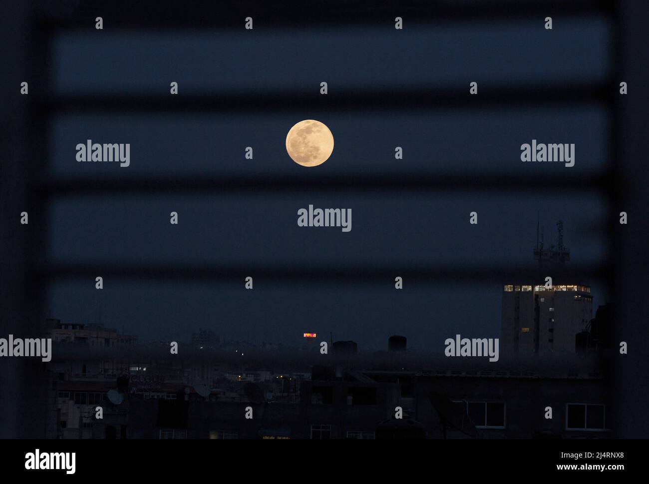 La piena "luna rosa" sorge sulla città di Gaza nel mezzo del Ramadan. Questo fenomeno astronomico può essere visto nella luna piena durante il mese di aprile dal tramonto fino all'alba. Gaza. Foto Stock