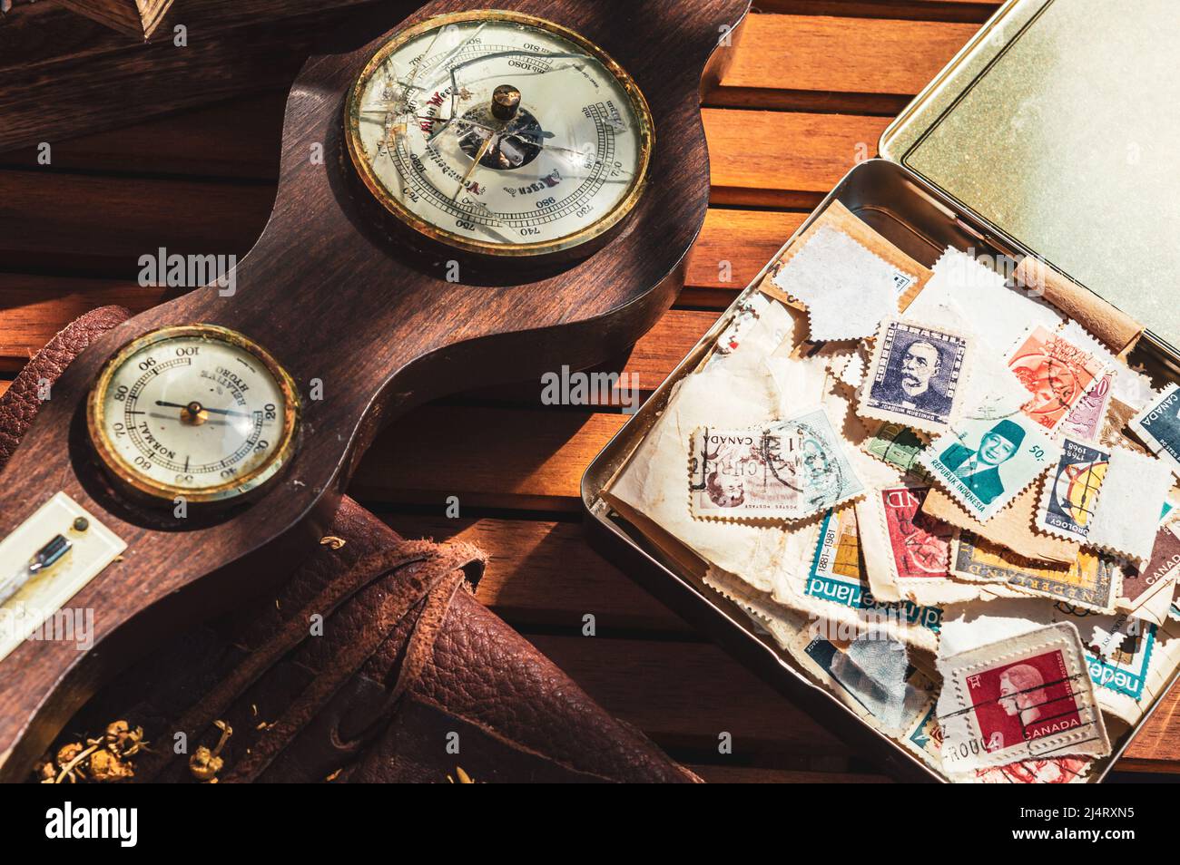 Immagine di un vecchio barometro e di una scatola di sigari con una collezione di vecchi francobolli. Foto Stock